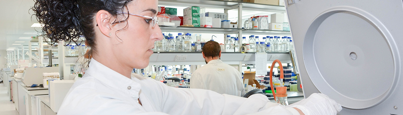 Researcher in white lab coat using machine
