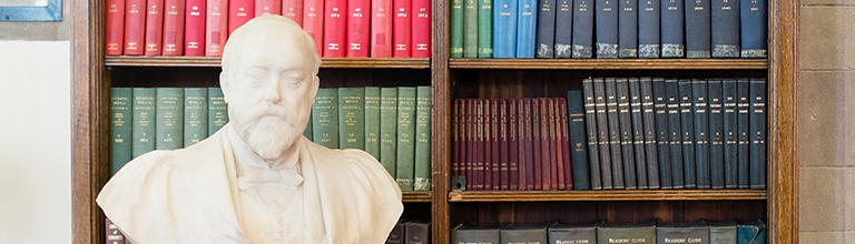 Bust of professor in front of library bookshelf