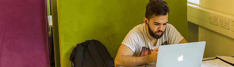 Male student using his laptop in the common room 