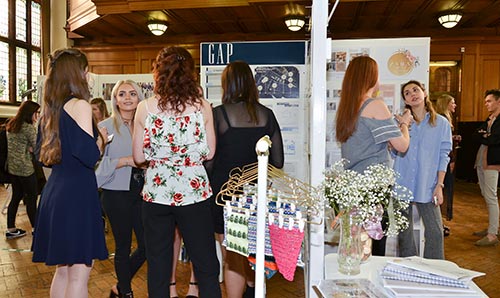 Students talking with businesses at a fashion degree show