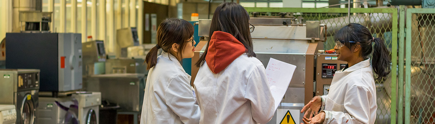 Students in lab coats discussing their work