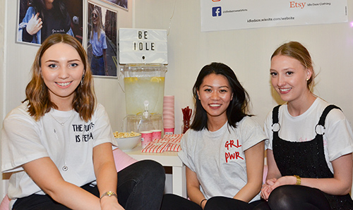 Female fashion students smiling in front of their project work