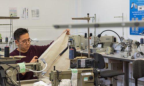 Male student using sewing equipment in a sewing lab