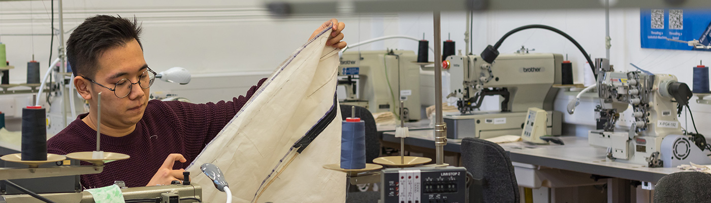 Male student using sewing equipment in a laboratory