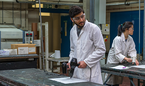 Male student in lab coat working in the screen printing lab