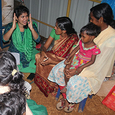 A woman teaching adults and children in Kerala, India