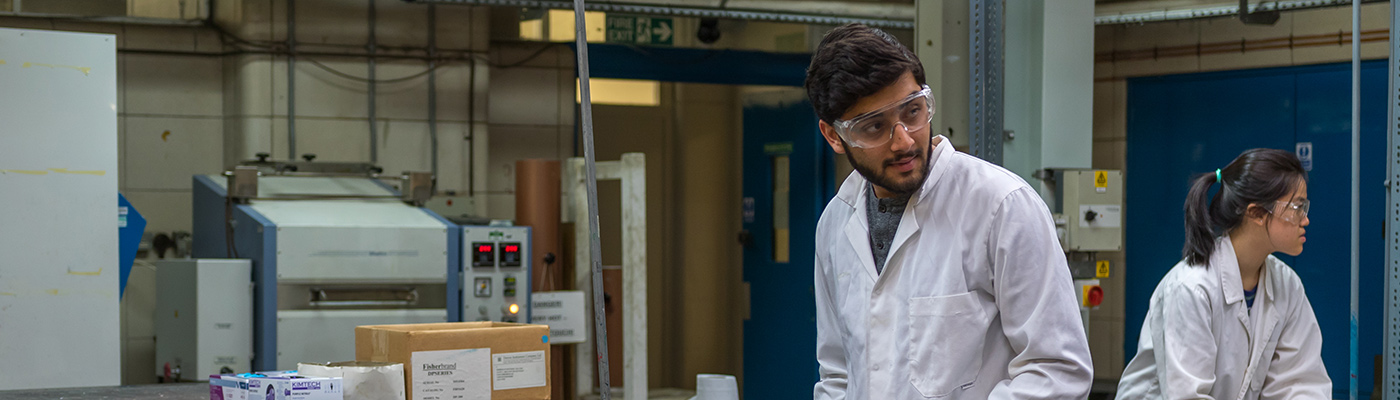 Male student in lab coat working in the screen printing lab