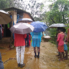 People in Kerala, India stood in the mud and holding umbrellas