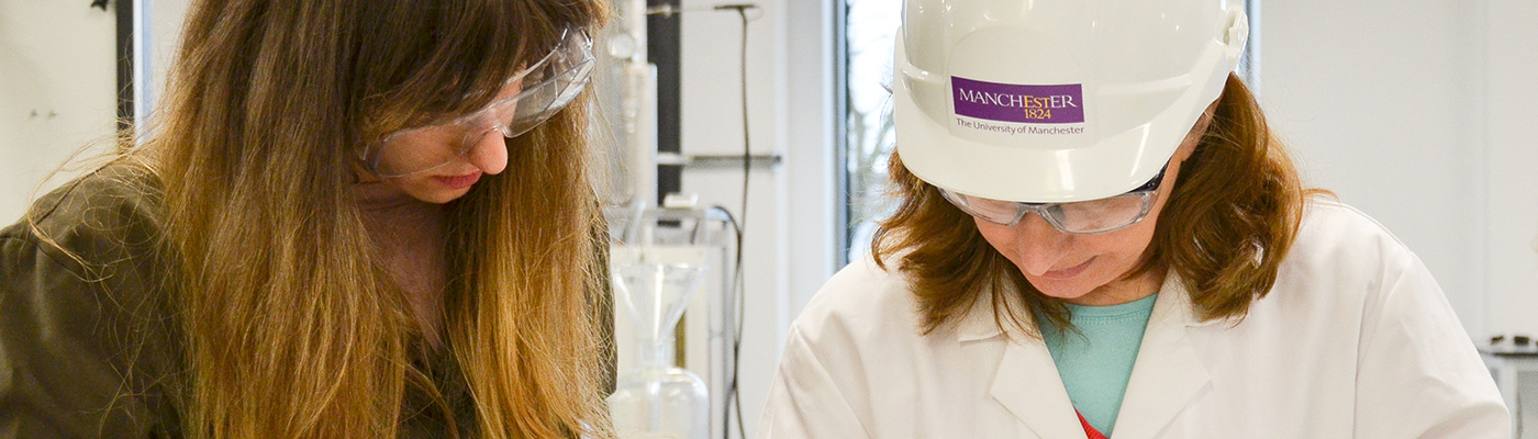 Two female student researchers looking down at their work