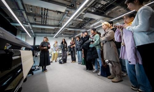 Teaching session in a materials lab with a presenter demonstrating equipment to a group of students.