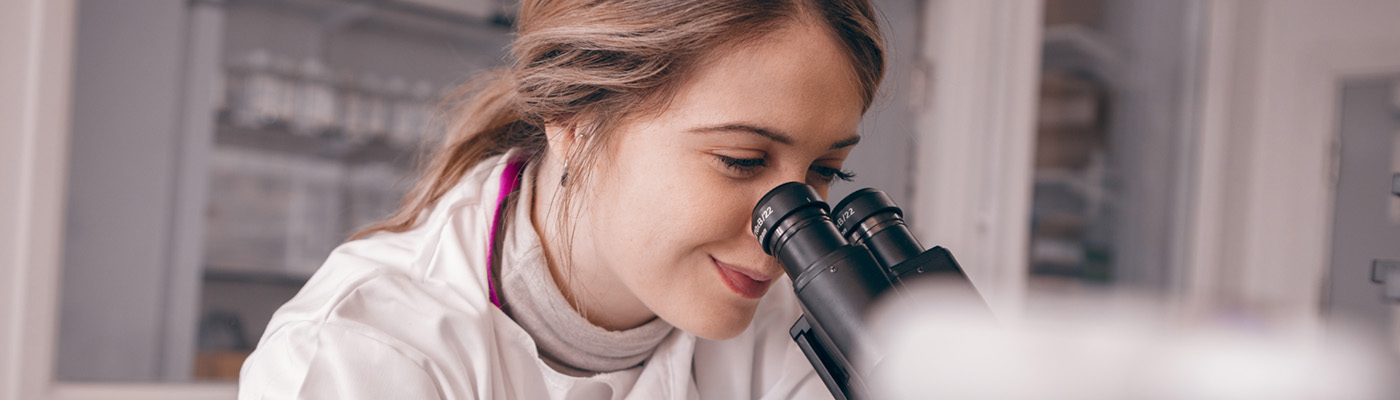 A female scientist looks down a microscope