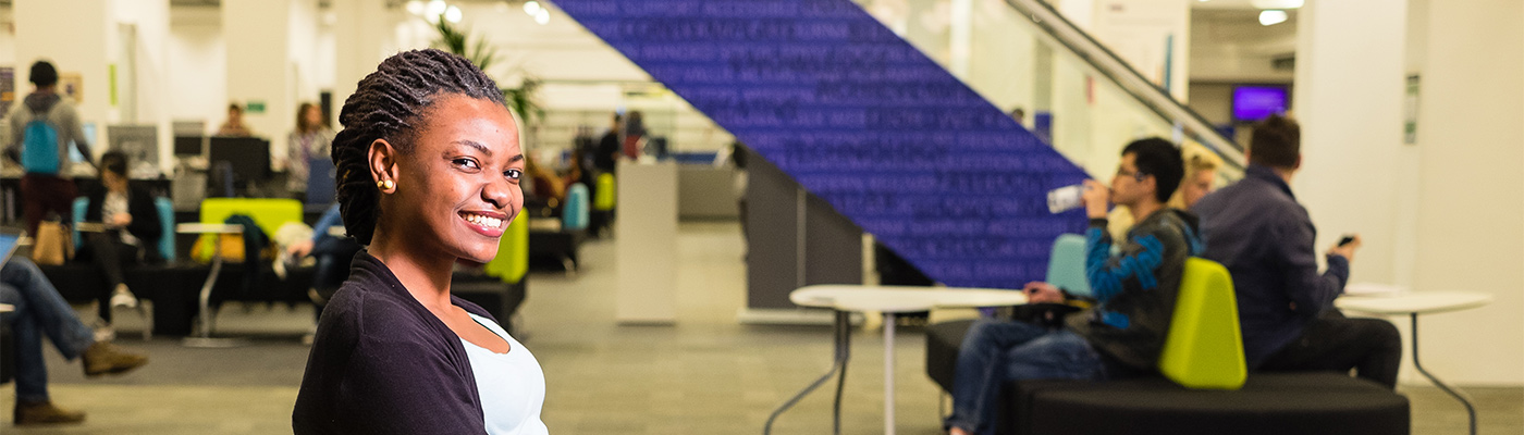 Student sat at desk, smiling at camera