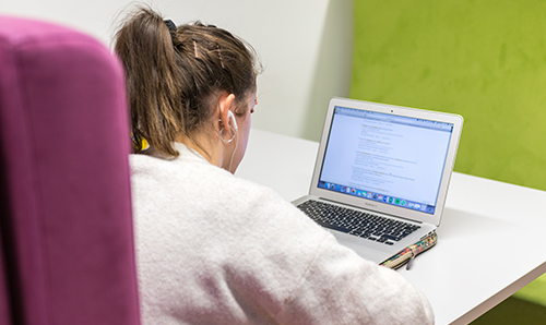 Female student looking at her laptop with her earphones in