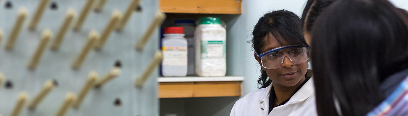 Female student in a lab coat in discussion with others